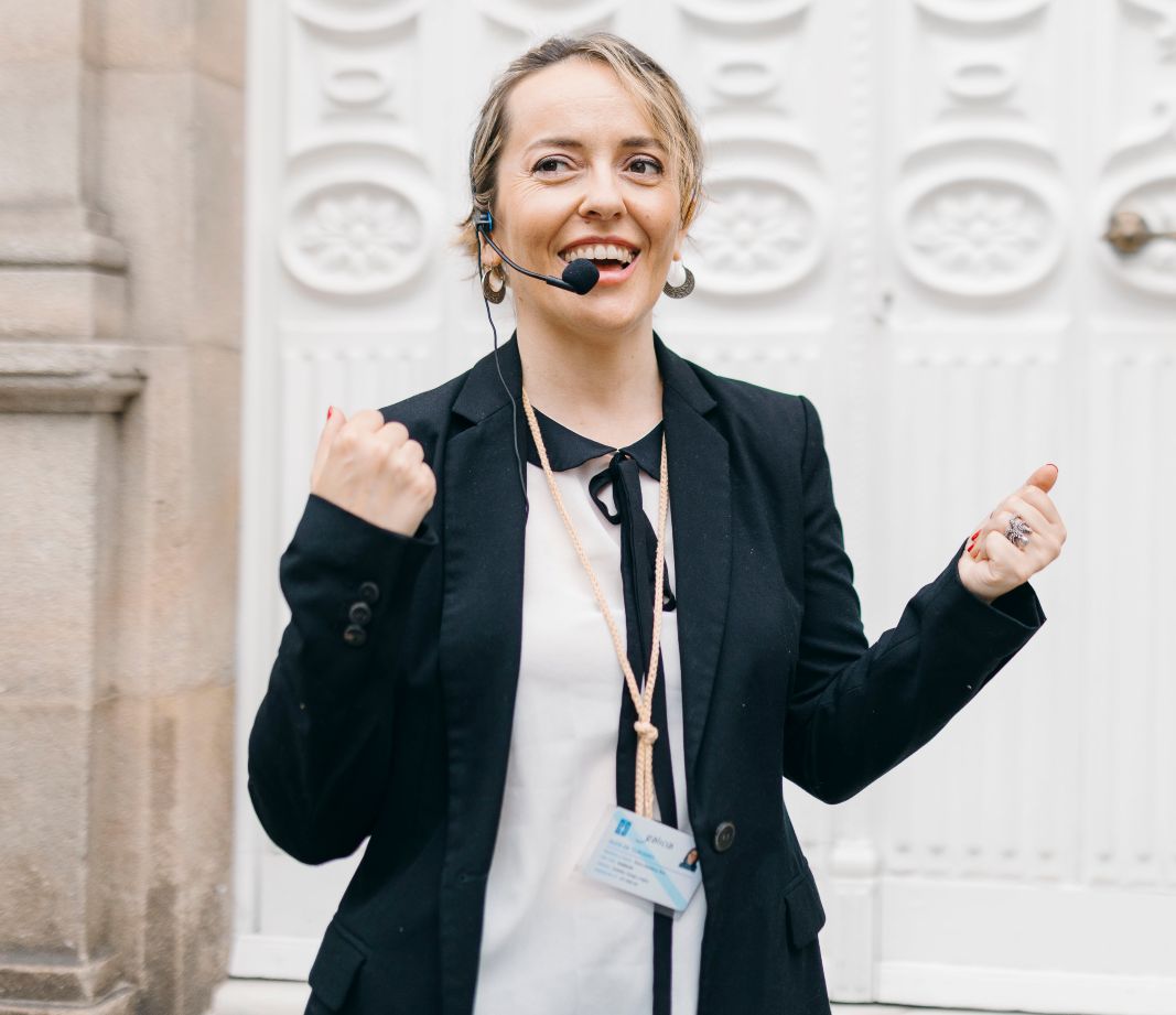 Ana Neira, guía turística, sonríe con entusiasmo y energía positiva mientras habla a través de sus auriculares con micrófono.